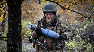 A Ukrainian soldier carries a shell with a written message to the Russian army, in the front line position near Bakhmut, in the Donetsk region, Ukraine, Oct. 27, 2022