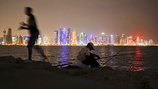 In this Nov. 2, 2018 picture, men fish, backdropped by the city skyline Doha, Qatar.