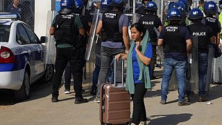 Μετανάστρια με την βαλίτσα της αποχωρεί από το κέντρο φιλοξενίας μεταναστών Πουρνάρα στην Κύπρο μετά τα επεισόδια στις εγκαταστάσεις