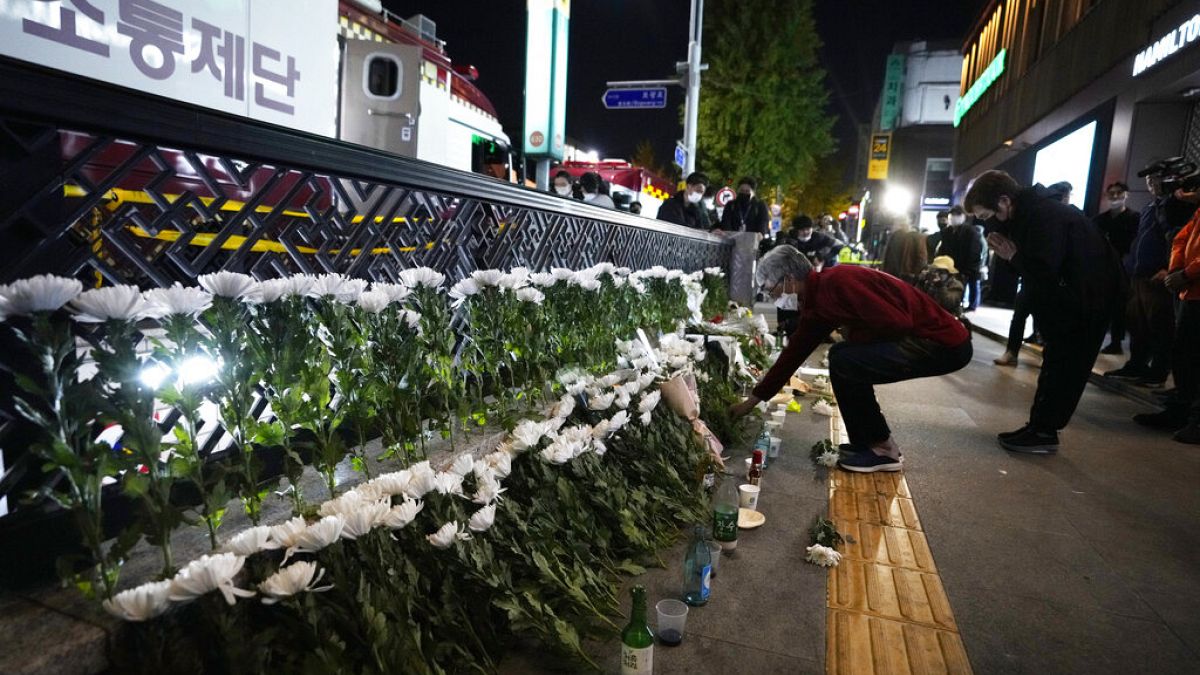 Una mujer coloca flores para rendir homenaje a las víctimas cerca del lugar de un accidente mortal en Seúl, Corea del Sur, el domingo 30 de octubre de 2022