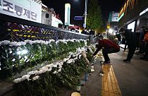 Una mujer coloca flores para rendir homenaje a las víctimas cerca del lugar de un accidente mortal en Seúl, Corea del Sur, el domingo 30 de octubre de 2022