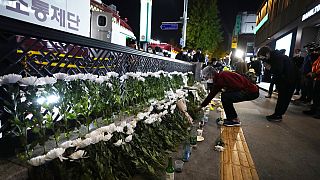 Una mujer coloca flores para rendir homenaje a las víctimas cerca del lugar de un accidente mortal en Seúl, Corea del Sur, el domingo 30 de octubre de 2022