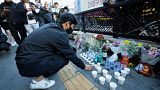 A man offers cups of wine to pay tribute for victims near the scene of a deadly accident in Seoul, South Korea, Sunday, Oct. 30, 2022, after Saturday's Halloween festivities.
