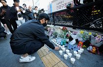 A man offers cups of wine to pay tribute for victims near the scene of a deadly accident in Seoul, South Korea, Sunday, Oct. 30, 2022, after Saturday's Halloween festivities.