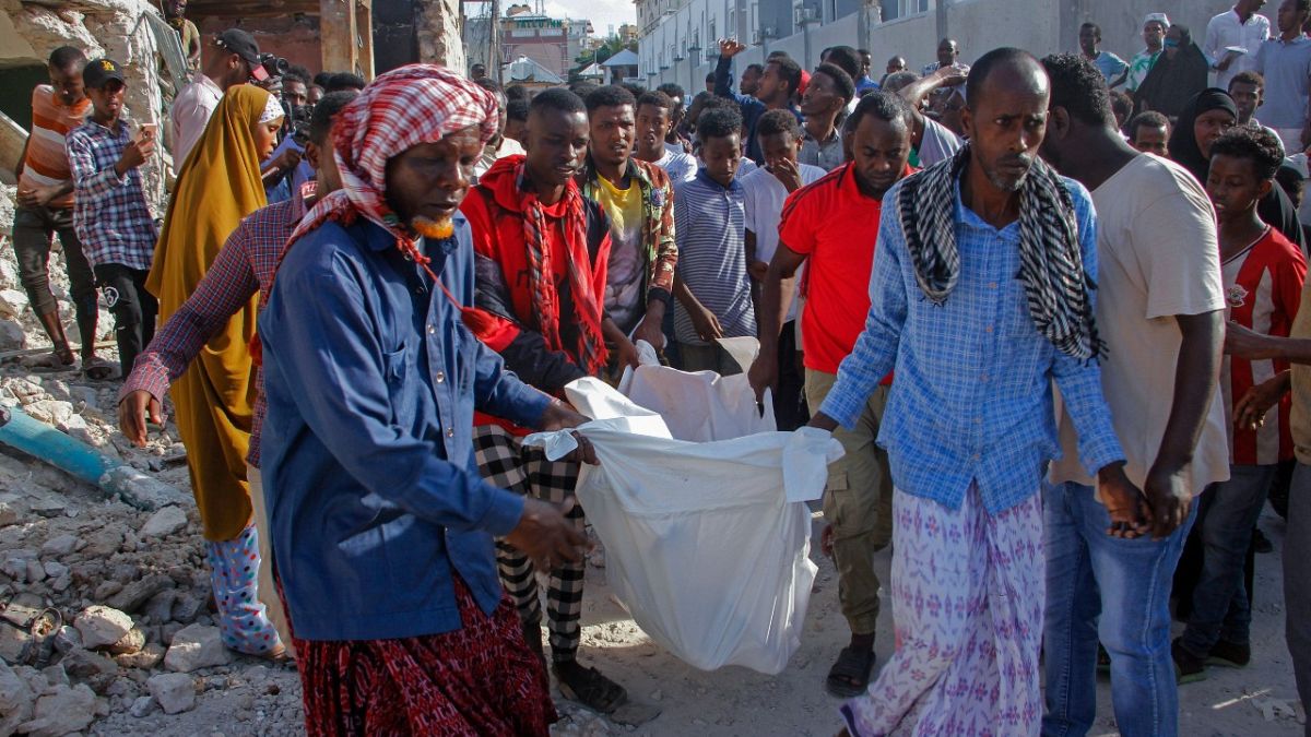 Relatives remove a body from the scene, a day after a double car bomb attack at a busy junction in Mogadishu, Somalia Sunday, Oct. 30, 2022.