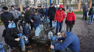 Varios ucranianos hacen cola para recoger agua en una fuente