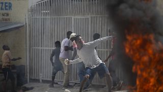 Un manifestante lanza una piedra a la policía durante una protesta por la muerte del periodista Romelson Vilsaint, en Puerto Príncipe, Haití, el domingo 30 de octubre de 2022.