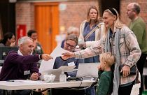 Eleitora acompanhada de uma criança recebe o boletim de voto em Vaerloese, Dinamarca