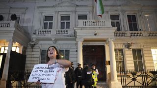 Протестующая с плакатом, требующим ввести санкции против иранских властей