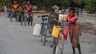 As mulheres de Machaze percorrem quilómetros de bicicleta ao calor para carregar bidões de água
