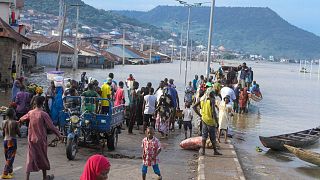 People were stranded due to floods following several days of downpours In Kogi, Nigeria, last month. THe Nigerian state gas company declared a force majeure.