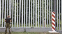 A Polish border guard patrols the area of a newly built metal wall near Kuznice.