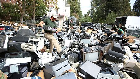 An e-waste worker wades through a sea of electronic items dropped at Mt. St. Mary's School for their annual recycling event, Grass Valley, California, Oct. 10, 2020.