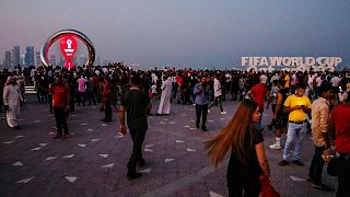 People take photographs in front of the official FIFA World Cup Countdown Clock on Doha's corniche, in Qatar.