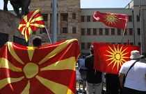 Old and current national flags are waved in front of the parliament building in Skopje.
