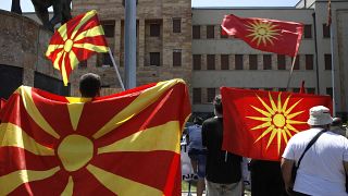 Old and current national flags are waved in front of the parliament building in Skopje.