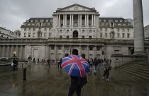 A woman with an umbrella stands in front of the Bank of England, at the financial district in London, Thursday, Nov. 3, 2022.