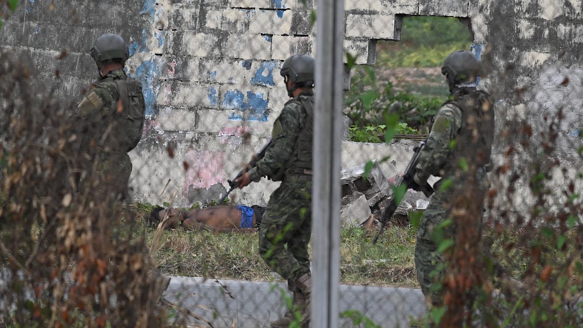 جنود يمشون بجوار جثة أحد السجناء عند سور لسجن ليتورال في غواياكيل، الإكوادور، في 2 نوفمبر 2022.