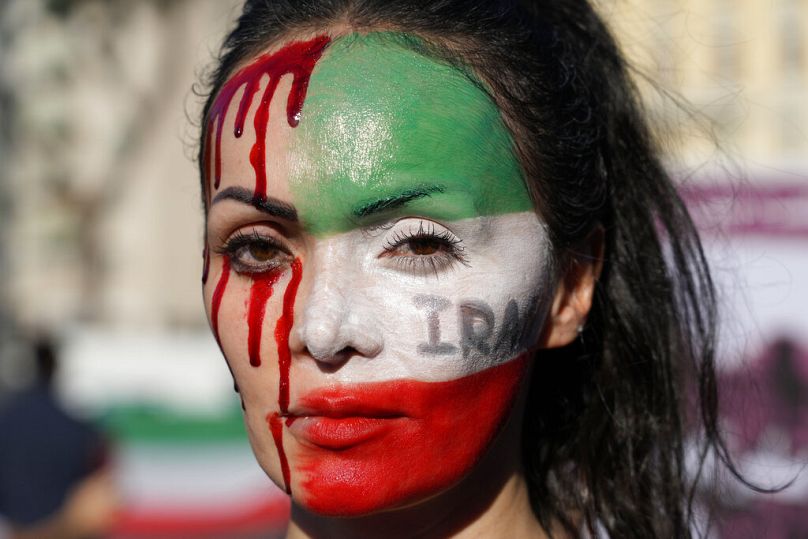 A woman is painted on a her face during a protest against the death of Mahsa Amini, a woman who died while in police custody in Iran, during a rally in central Rome, Oct. 2022
