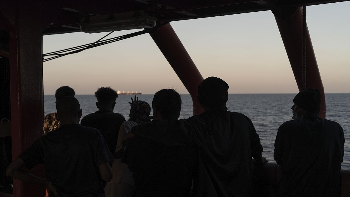 Migrants rescued in the Mediterranean Sea stand onboard of the Ocean Viking rescue ship.