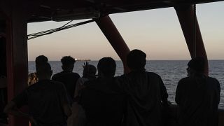 Migrants rescued in the Mediterranean Sea stand onboard of the Ocean Viking rescue ship.