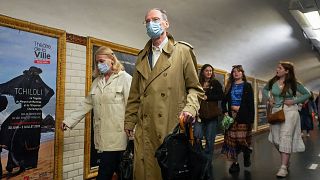People wearing face masks to protect against COVID-19 rushes to a subway platform in Paris.
