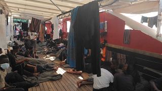 Rescued people resting on the floor of the open deck aboard the Ocean Viking. 