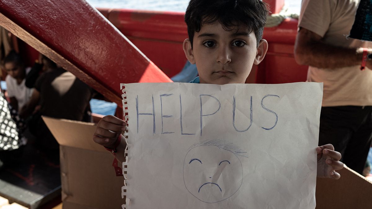 Un enfant migrant tient une pancarte à bord du navire Ocean Viking naviguant dans le détroit de Sicile, en mer Méditerranée, le 2 novembre 2022.