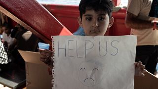 Un enfant migrant tient une pancarte à bord du navire Ocean Viking naviguant dans le détroit de Sicile, en mer Méditerranée, le 2 novembre 2022.