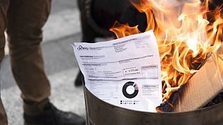 A utility bill burns during a protest by shopkeepers against the costs of living, in Turin, Italy, Tuesday, Oct. 11, 2022.