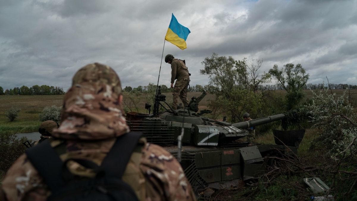 Ukrán zászlót tűz ki egy ukrán katona egy orosz tankra Harkivban 2022. szeptember 19-én