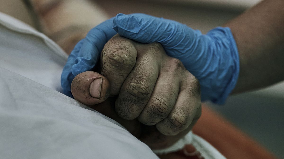A medic holds hand of a Ukrainian soldier wounded in a battle with the Russian troops in a city hospital in Mykolayiv, 3 November 2022
