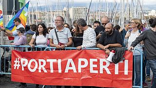 Ativistas pelos direitos dos migrantes seguram faixa onde se lê "Portas Abertas", em Sicília, Itália