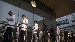 Customers line up outside of an Apple Store before its opening on the first day of sale for the Apple iPhone 14 in Beijing, China.