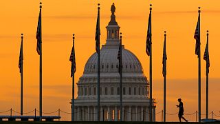 An early morning pedestrian is silhouetted against sunrise as he walks through the U.S. Flags on the National Mall and past the US Capitol Building in Washington