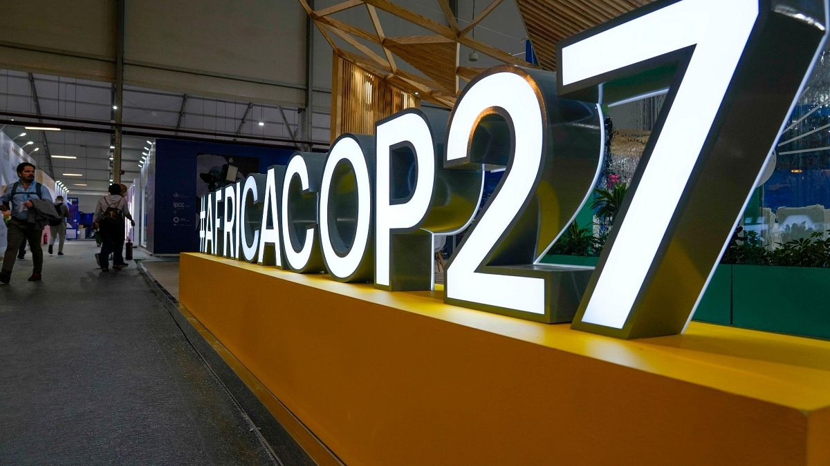 People pass a booth at the convention center hosting the COP27. 