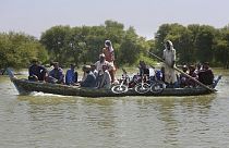 Villagers with their belongings cross a flooded area on a boat, in Dadu, a district of southern Sindh province, Pakistan, Sept. 23, 2022.
