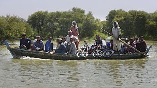 Villagers with their belongings cross a flooded area on a boat, in Dadu, a district of southern Sindh province, Pakistan, Sept. 23, 2022.