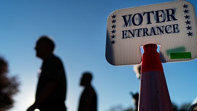 Voters pass a sign outside a polling site in Warwick, R.I., Monday, Nov. 7, 2022, after casting their ballots on the last day of early voting before the midterm election.