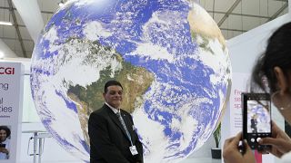 Участник COP27 на фоне инсталляции "Планета Земля"