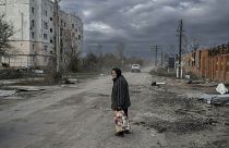 Жительница поселка Архангельское, Херсонской области на фоне разрушенных домов