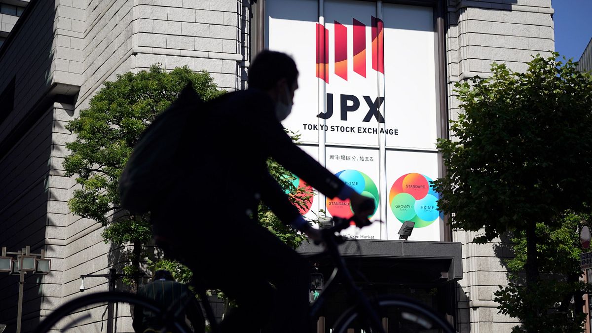 Tokyo Menkul Kıymetler Borsası'nın önünden geçen bir bisikletli kişi