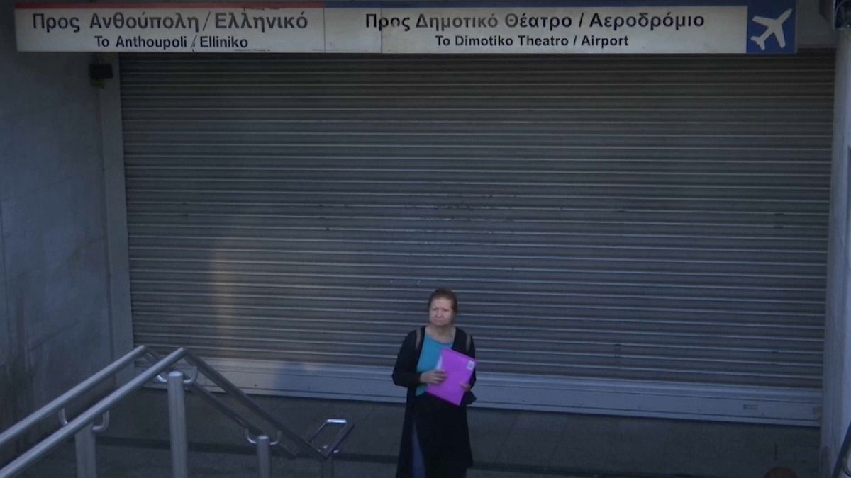 Una mujer espera frente a una entrada de metro cerrada por la huelga en Atenas, Grecia. 
