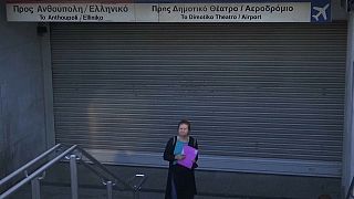 Una mujer espera frente a una entrada de metro cerrada por la huelga en Atenas, Grecia.