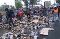 Los transeúntes recogiendo las latas de cerveza derramadas por el camión