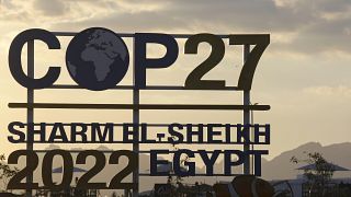 The sun sets behind signage for the COP27 U.N. Climate Summit in Sharm el-Sheikh, Egypt, Wednesday, Nov. 9, 2022. 