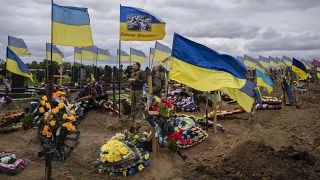Dos soldados de la guardia nacional beben un chupito para honrar la memoria de dos soldados fallecidos en el cementerio de Kharkiv, en el este de Ucrania