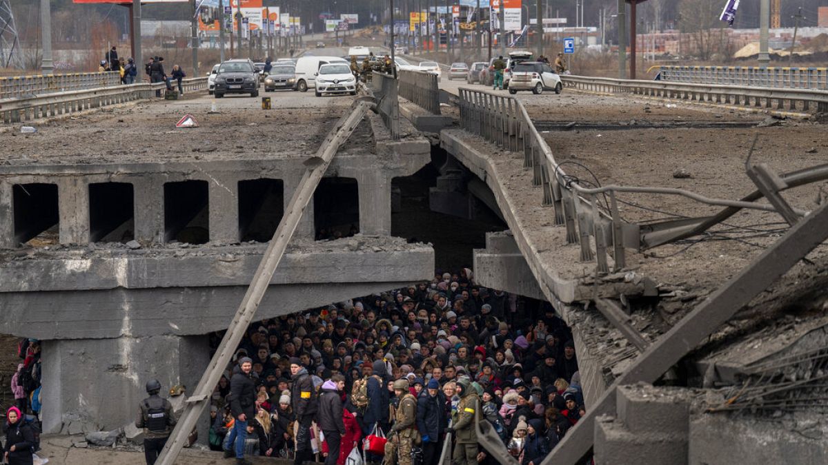Des Ukrainiens se massent sous un pont détruit alors qu'ils tentent Irpin, en Ukraine, samedi 5 mars 2022.