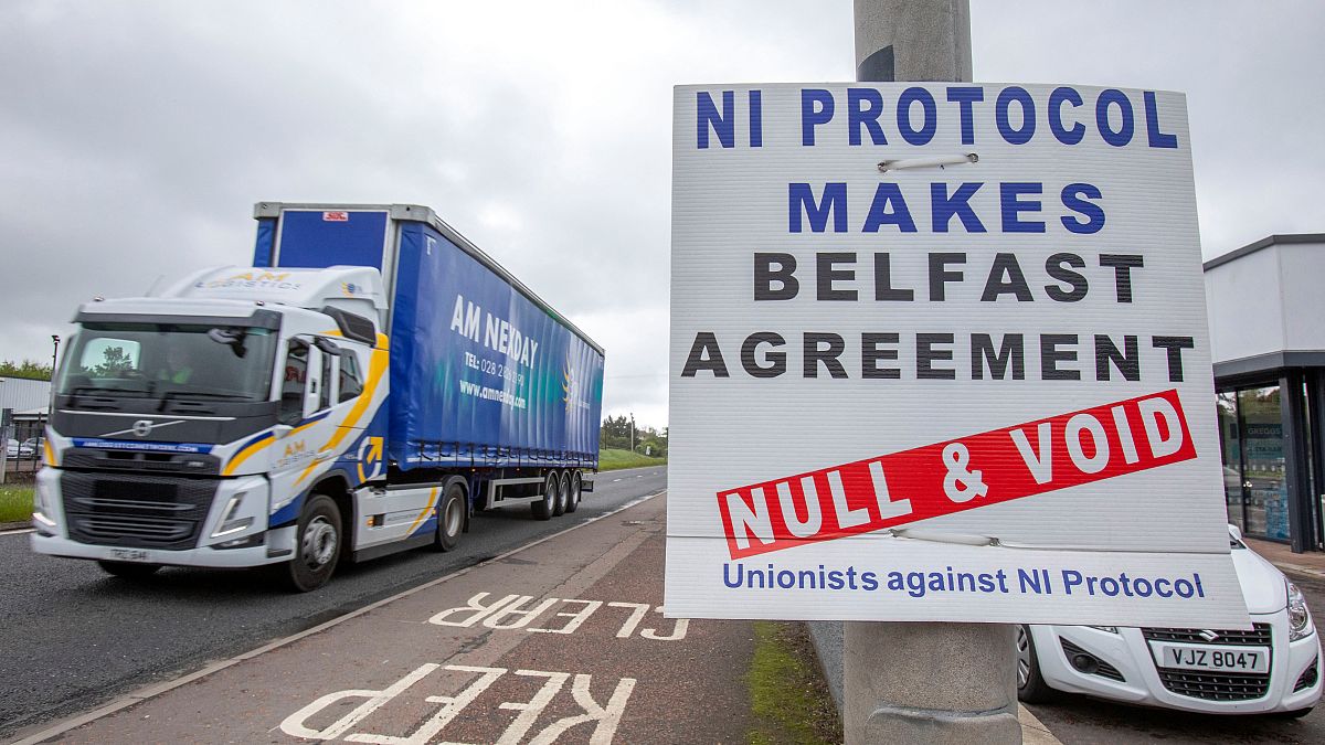 A lorry passes an anti 'Northern Ireland Protocol' sign as it is driven away from Larne port, north of Belfast in Northern Ireland, after arriving on a ferry, on May 17, 2022.