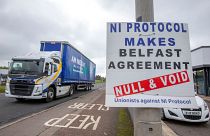 A lorry passes an anti 'Northern Ireland Protocol' sign as it is driven away from Larne port, north of Belfast in Northern Ireland, after arriving on a ferry, on May 17, 2022.